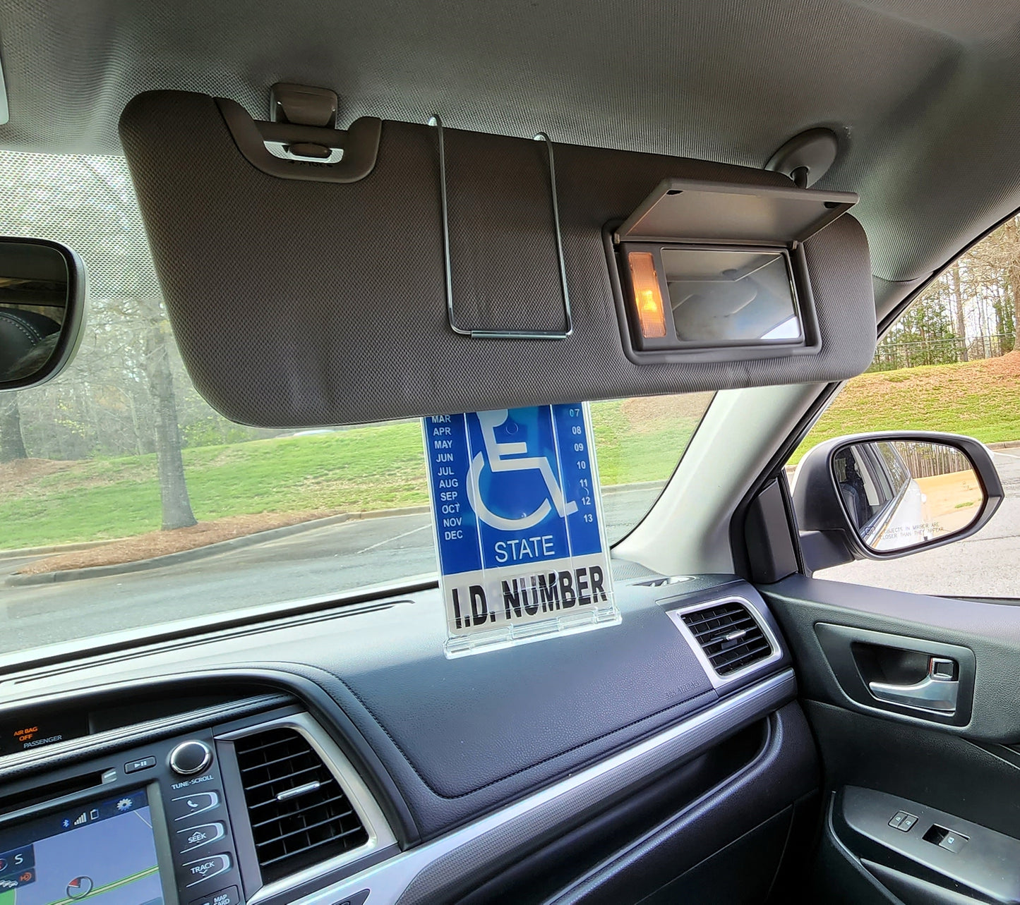Visor mounted handical parking placard holder.  Clips to visor, and magnetically held in off position